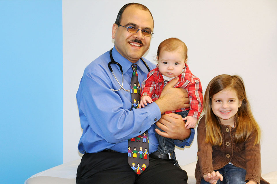 Dr Sayed Holding baby patient girl patient sits next to him| Bright Future Pediatrics